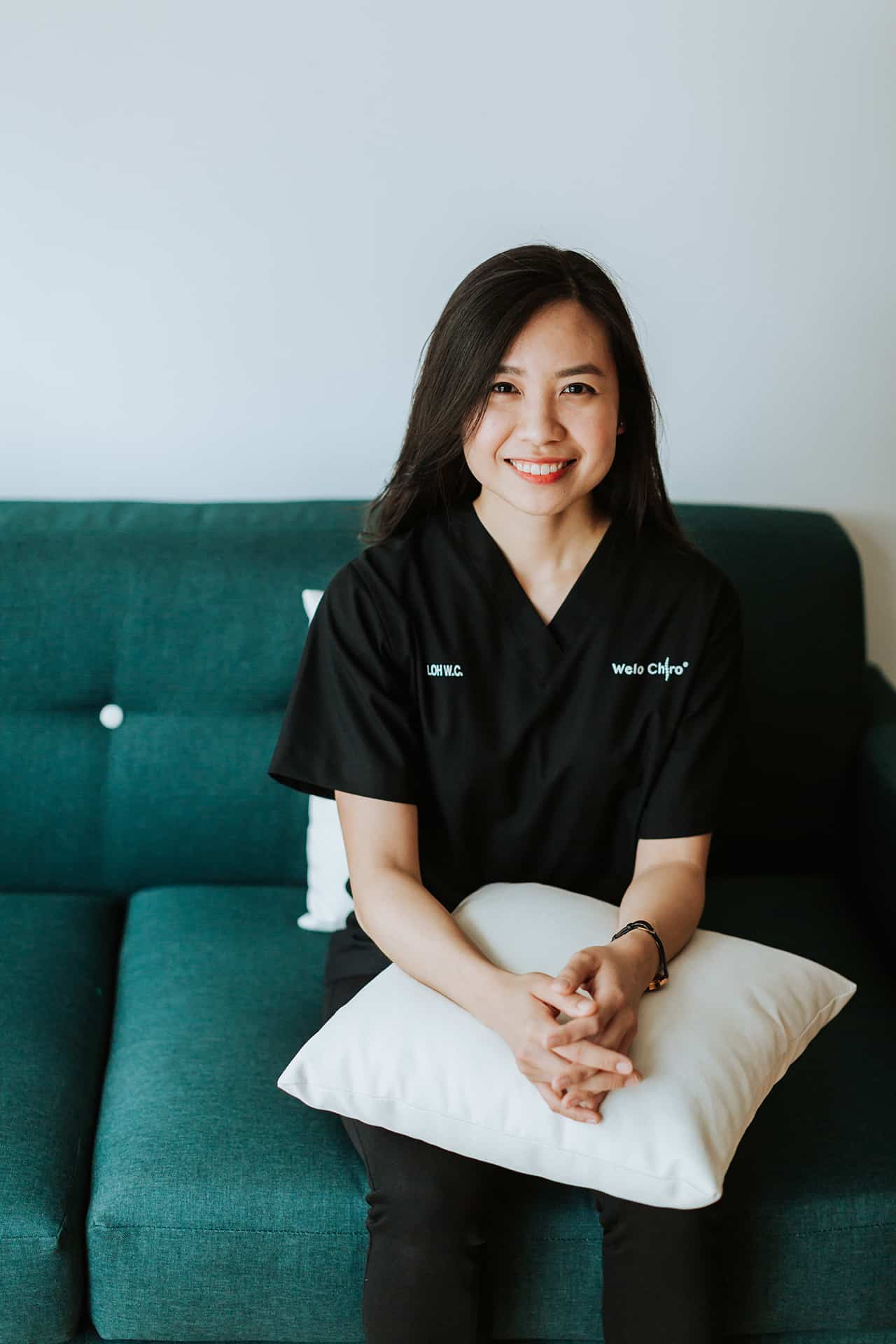 Portrait of Dr Loh Wei Chee, seated, wearing black Welo scrubs