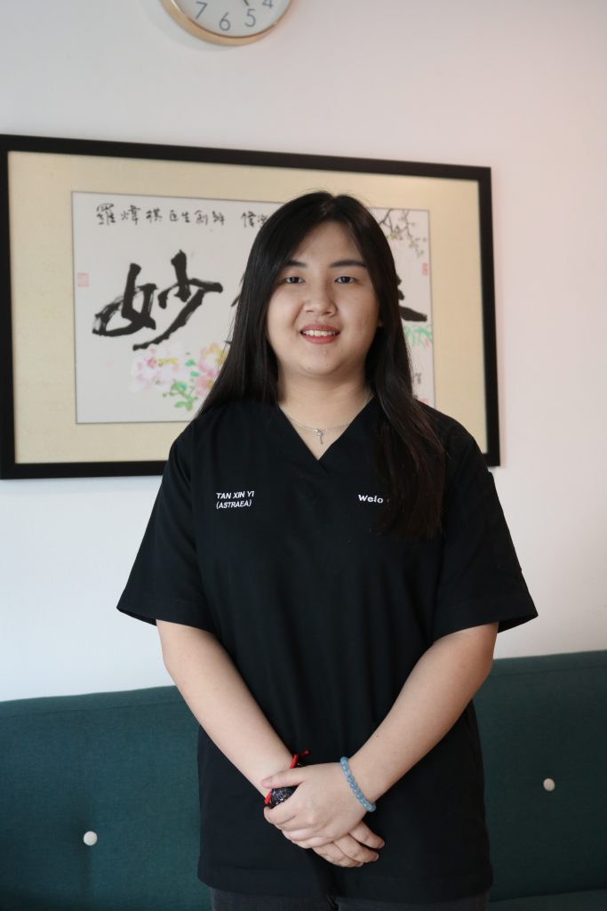 Portrait of Dr Xin Yi, wearing black scrubs